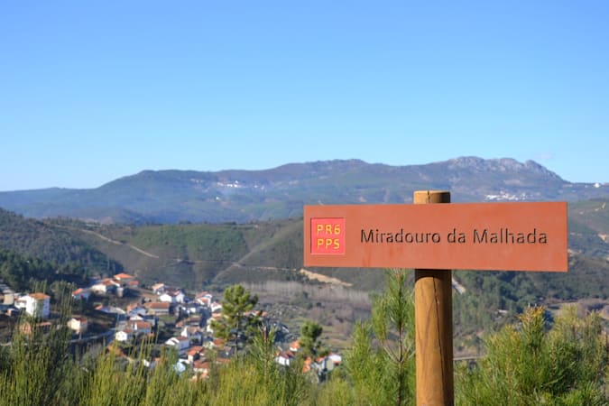 placa a assinalar um miradouro com uma aldeia ao fundo e montanhas no horizonte