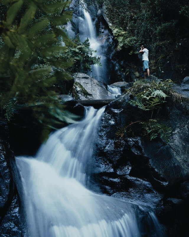 home a tirar fotografia de uma cascata na floresta