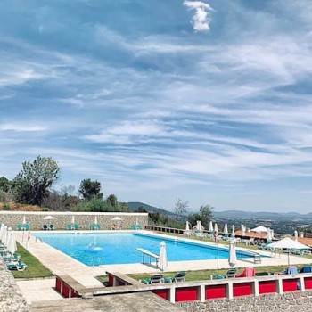 grande piscina de água azul com relva à volta