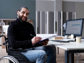 homem alegre em cadeirade rodas no escritório