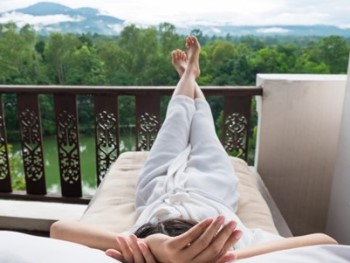 mulher deitada a relaxar na varanda co, vista para a natureza